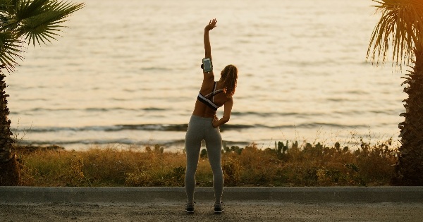 Woman stretching by the sea at sunrise, representing energy and intentional productivity