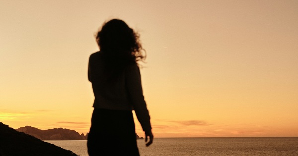 Silhouette of a woman looking at the sea at sunset, representing introspection and self-awareness